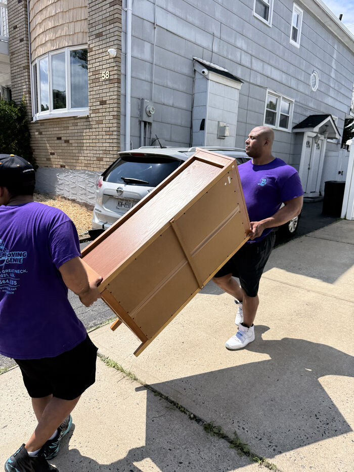 Moving Genie crew carrying a wooden dresser up the steps of an Astoria walk-up building