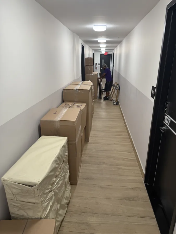 Wrapped furniture and boxes arranged along a building hallway