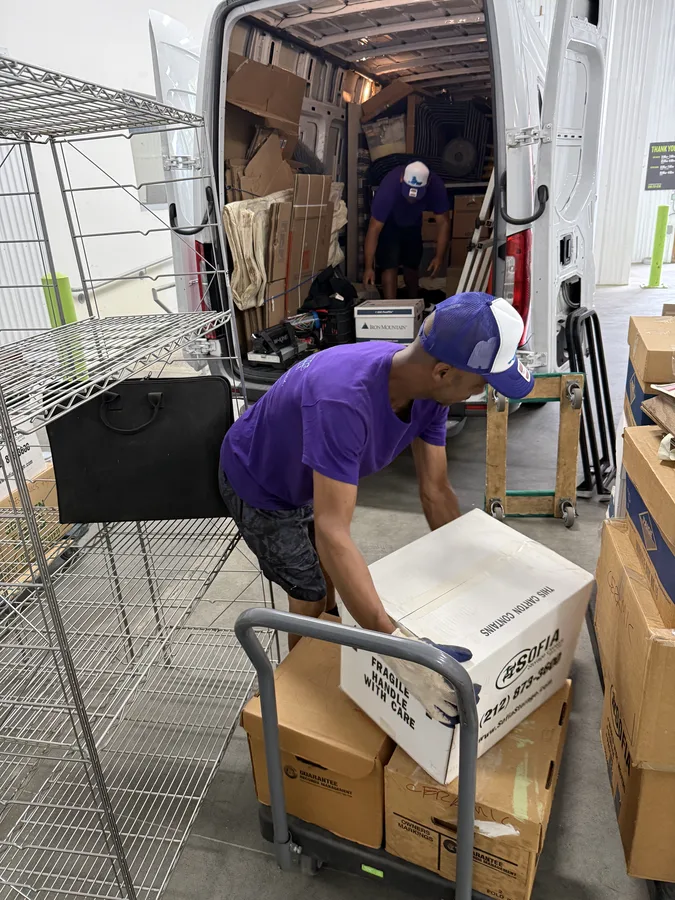 Mover placing a box onto a dolly beside the moving van