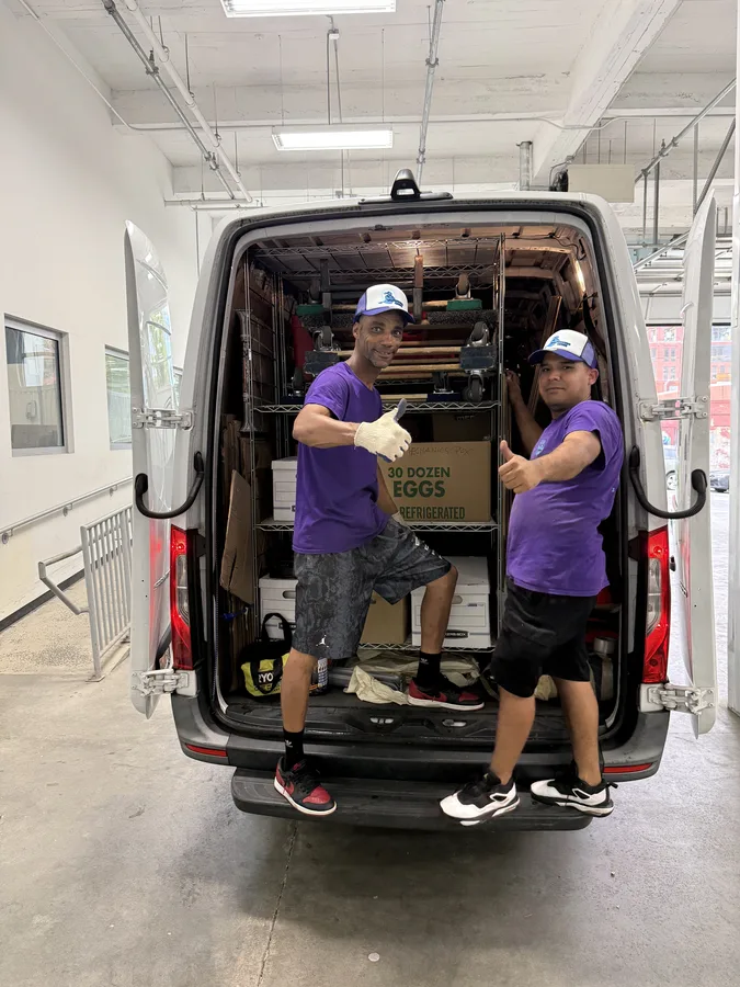 Two Moving Genie crew members at the open rear of a loaded van