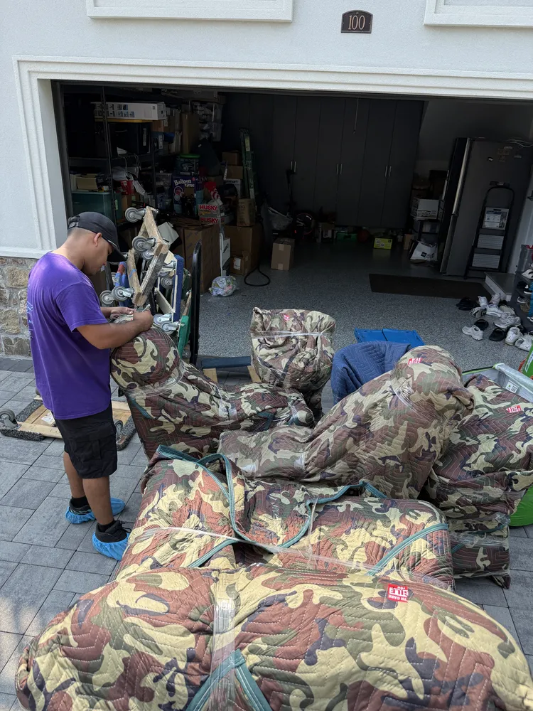 Moving Genie crew wrapping furniture with protective padding outside a garage